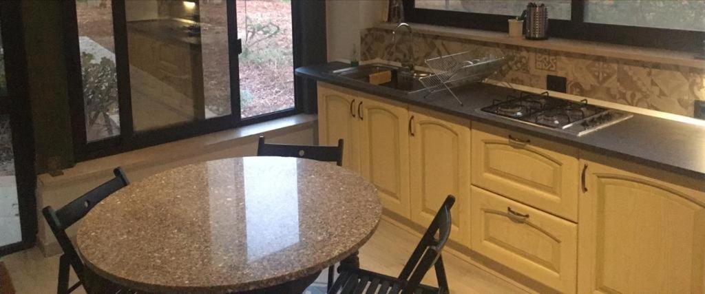 een tafel en stoelen in een keuken met een aanrecht bij La casa della Salvia con Piscina condivisa in campagna vicino al mare - Canestanco 18 in Santa Croce Camerina