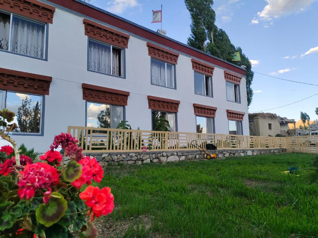 a building with red flowers in front of it at Norbooling HomeStay, Leh Ladakh in Leh