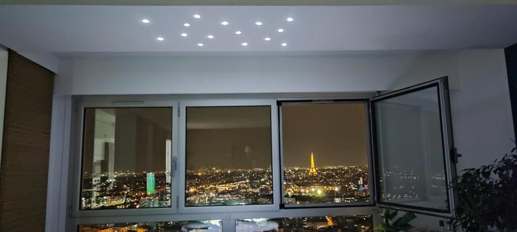 a room with a window with a view of a city at Full apt - Top floor - Eiffel Tower Panoramic View in Issy-les-Moulineaux