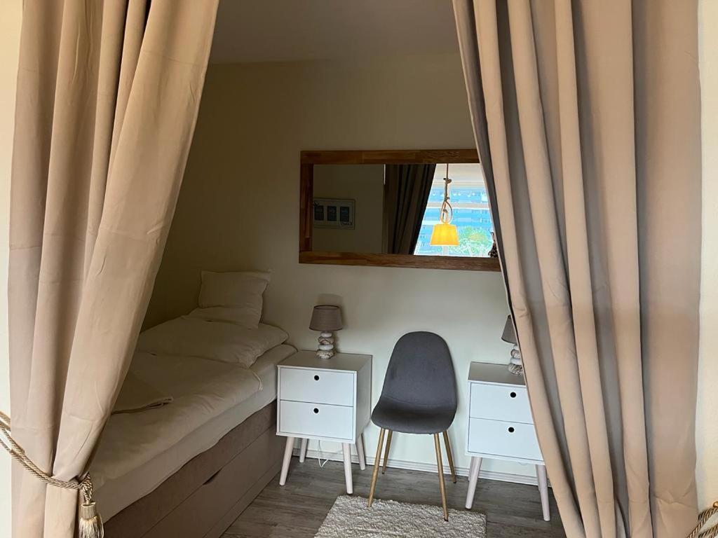 1 dormitorio con cama, espejo y silla en Ferienwohnung an der Ostsee, en Heiligenhafen