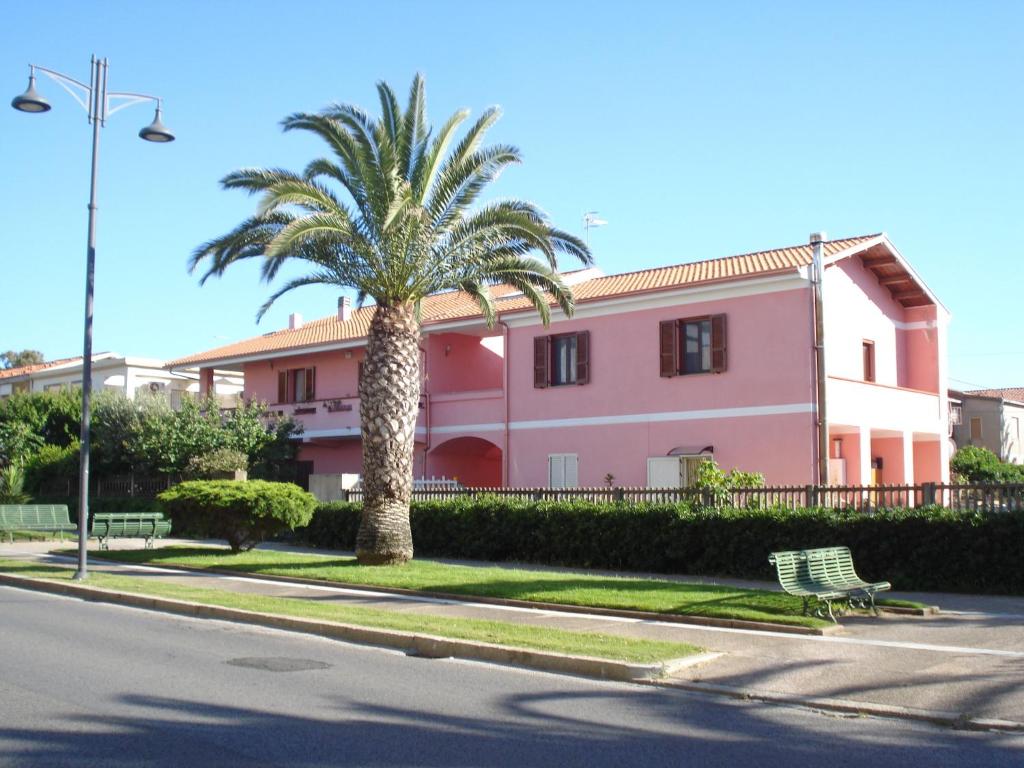 una palmera frente a un edificio rosa en L'Aurora Viola en Carbonia