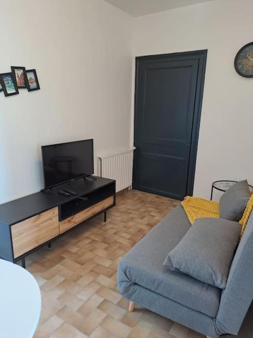 sala de estar con sofá y TV de pantalla plana en Chez Béatrice, en Saint-Jouan-des-Guérets