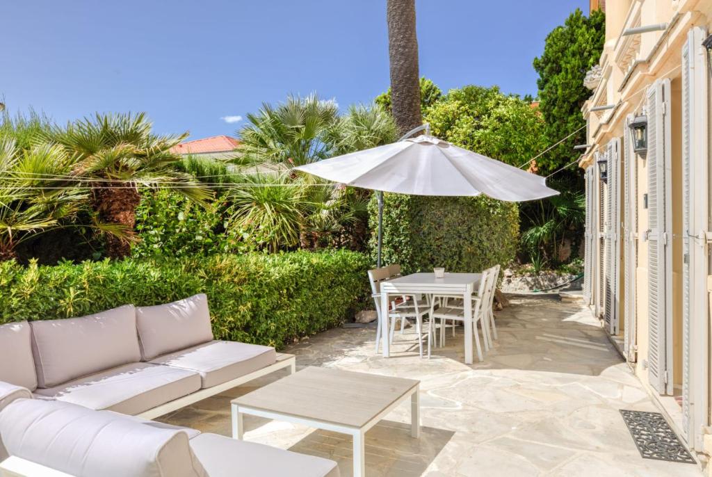 une terrasse avec un canapé, un parasol et une table dans l'établissement Mont Boron Exclusive Apartment in Villa Belle Époque, à Nice