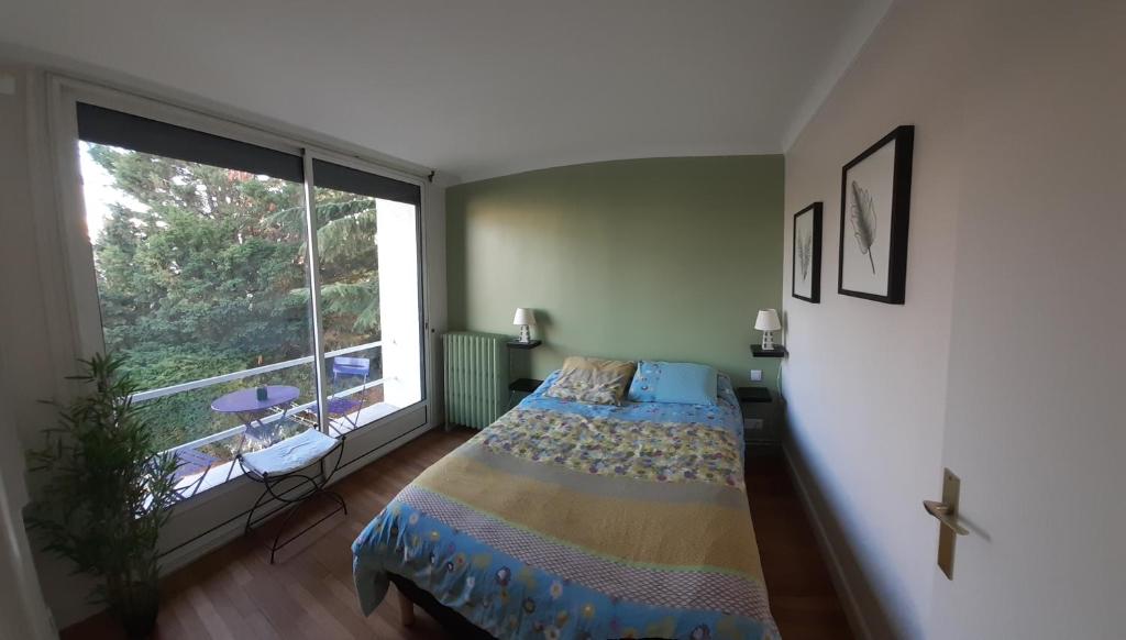 - une chambre avec un lit et une grande fenêtre dans l'établissement Chambre d'hôte proche Paris, à Épinay-sur-Seine