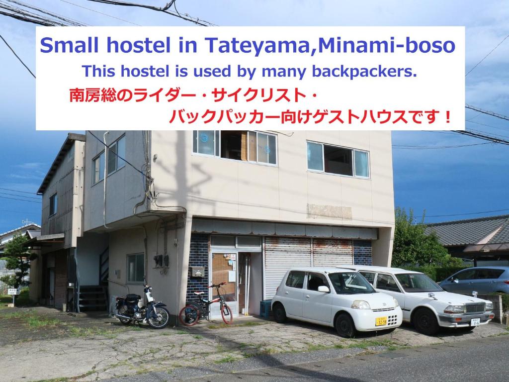 ein kleines Haus mit zwei Autos davor geparkt in der Unterkunft Tateyama Wheels Guest House in Tateyama