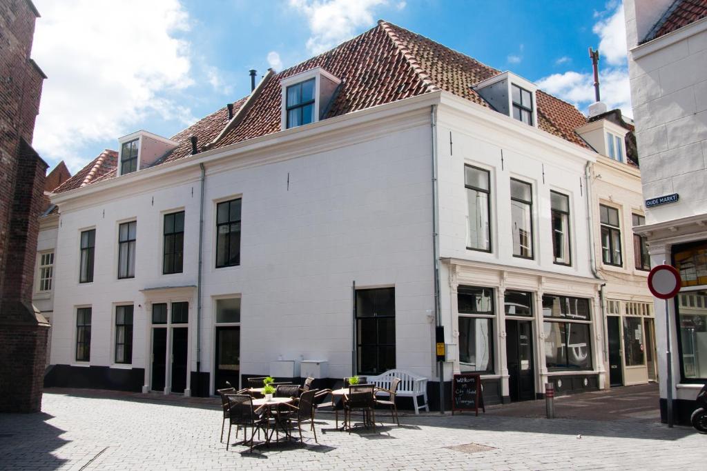 een wit gebouw met tafels en stoelen in een straat bij City Hostel Vlissingen in Vlissingen