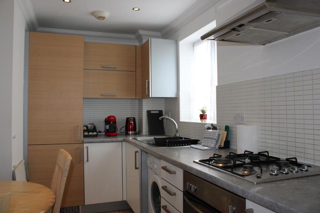 a kitchen with a stove top oven next to a table at Eldridge Court Apartment in Dagenham