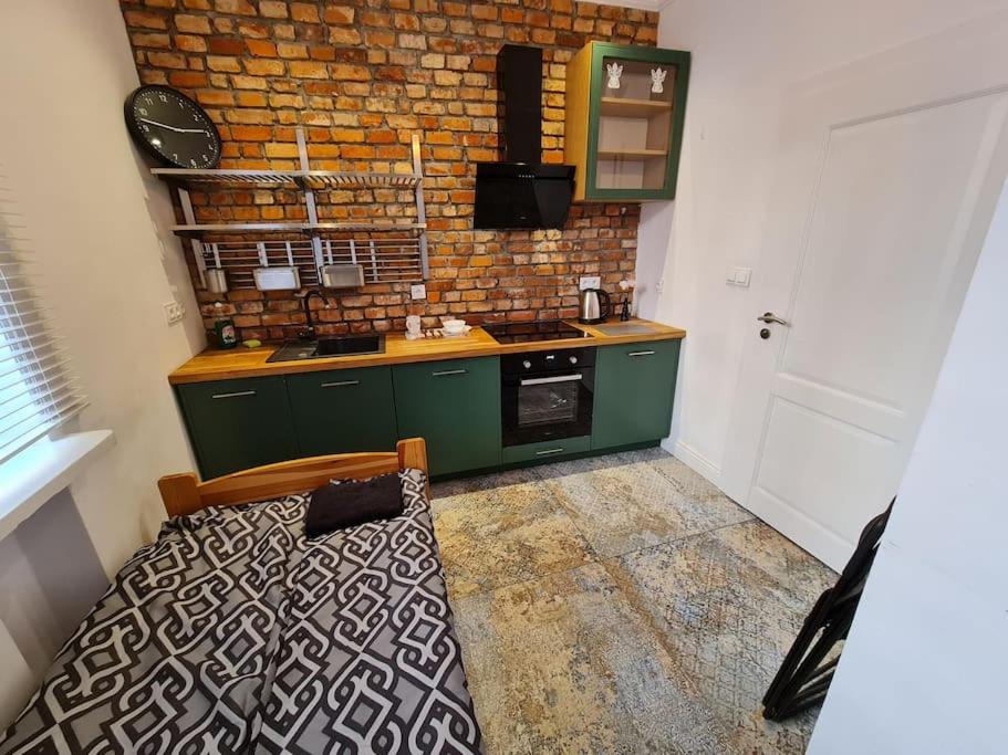 a kitchen with a bed and a brick wall at Fantastic Apartments - KP69 Room - A in Warsaw
