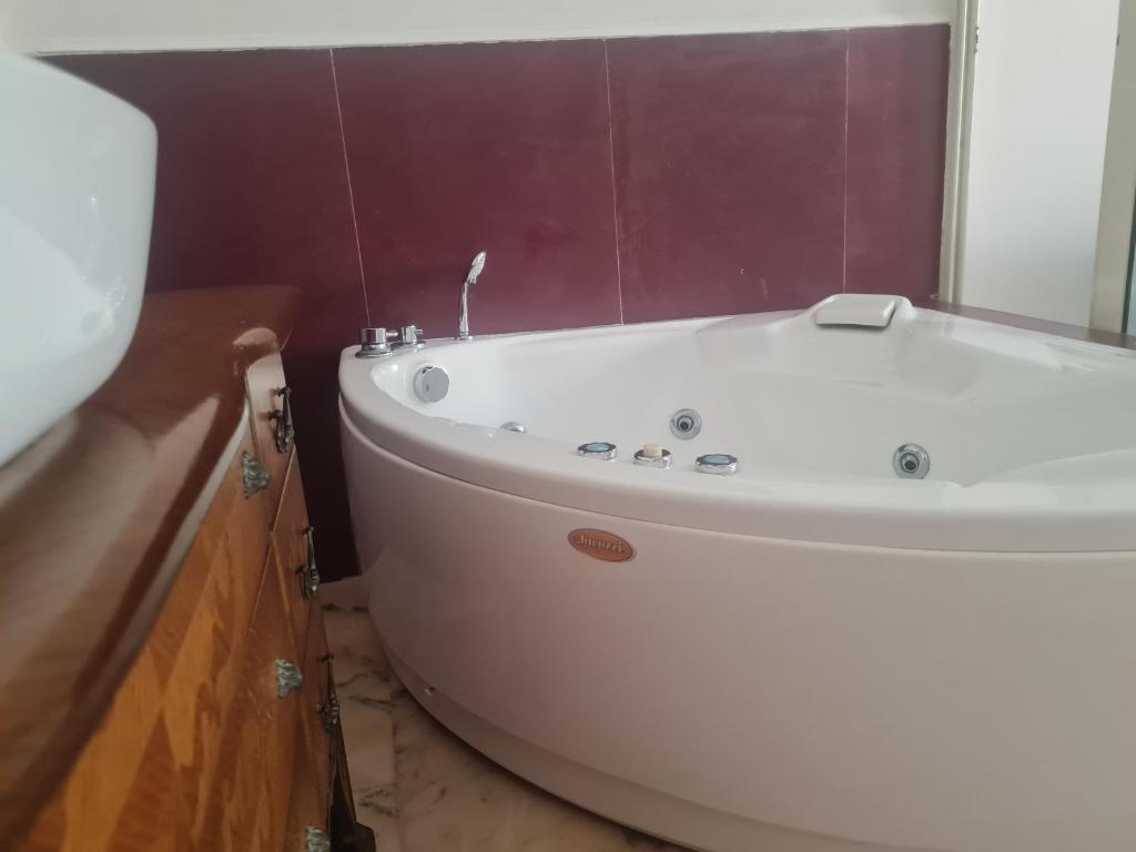a white bath tub in a bathroom with purple tiles at Don Ciccio GH in Bova Marina
