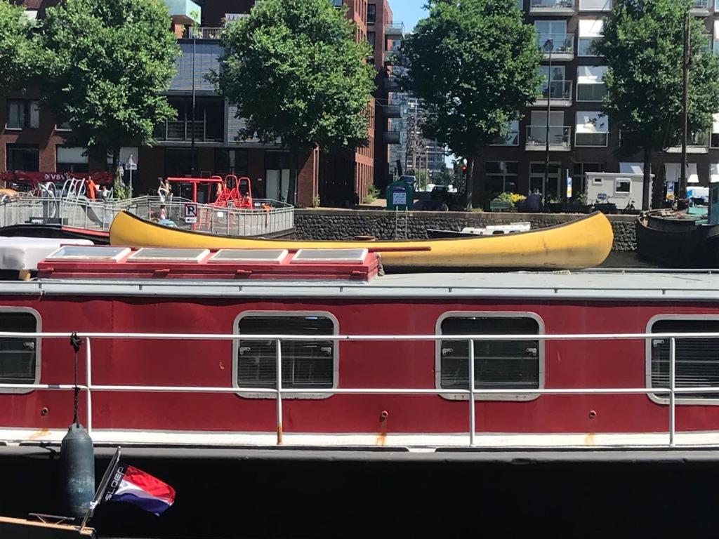 a red train with a yellow canoe on top of it at Spacious homely house boat in Amsterdam