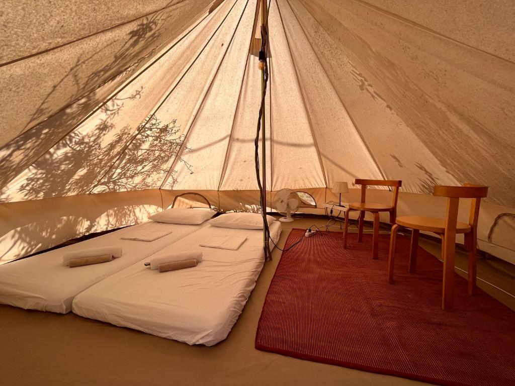 a bed in a tent with a table and chairs at La ViTa in land - between olives and almonds in Noto