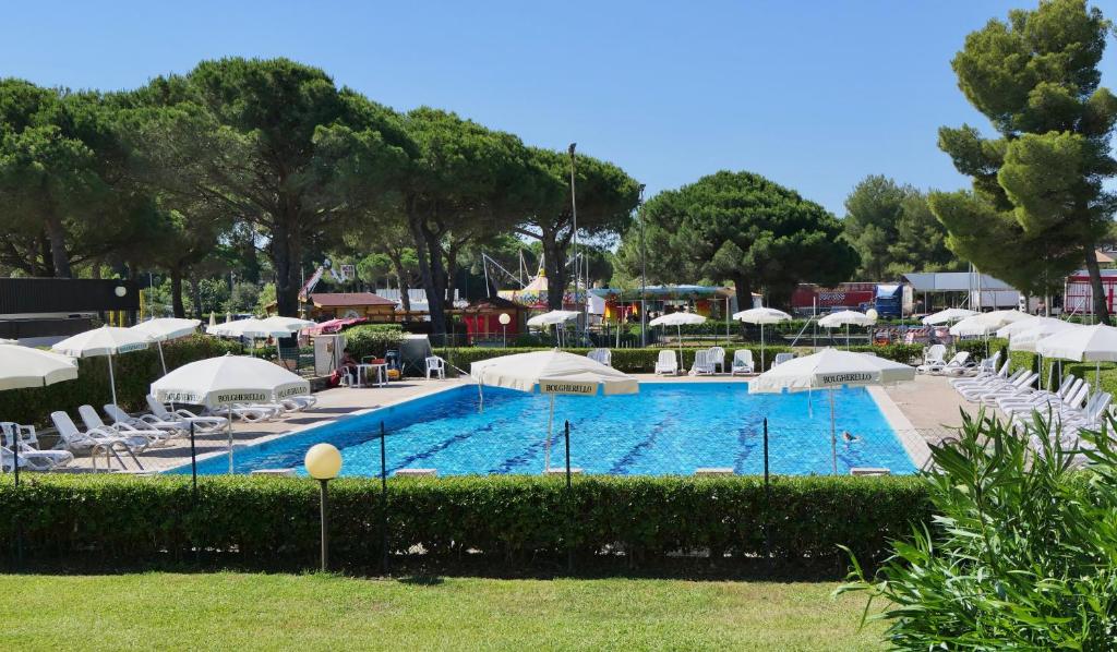 una gran piscina con sillas y sombrillas en ISA-Residence with swimming-pool in Marina d Bibbona at only 300 m from the beach, en Marina di Bibbona