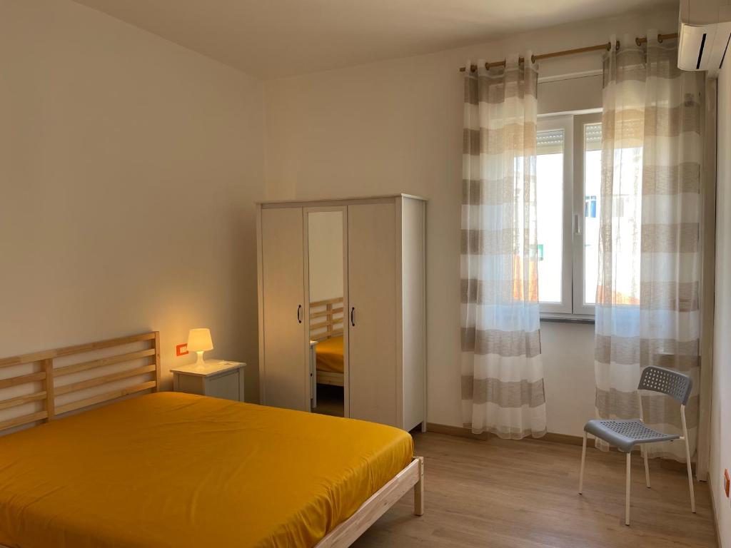 een slaapkamer met een geel bed en een stoel bij Appartamento Anemone in Termoli