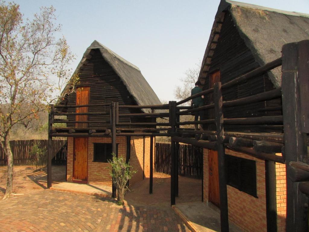 a house with a thatched roof and a fence at Forest Cabin at Loodswaai between Dinokeng and Cullinan 