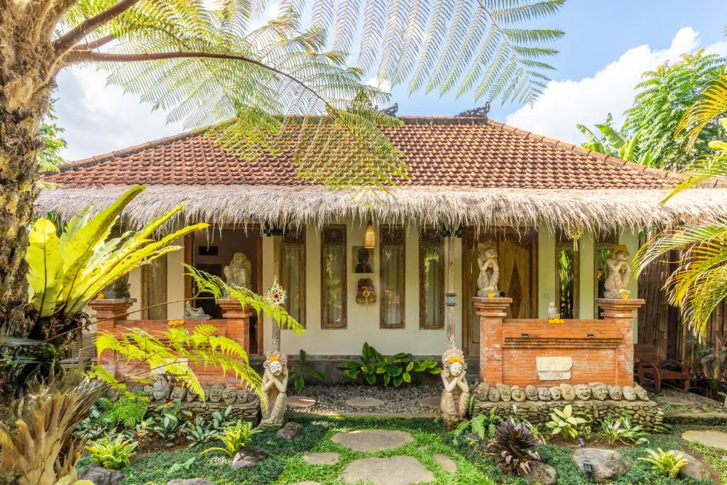 una casa en un jardín con una palmera en Villa Pranawa, en Ubud
