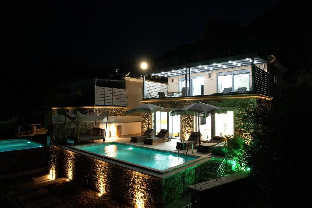 une maison avec une piscine la nuit dans l'établissement Goldeneye luxury Villas, à Parga