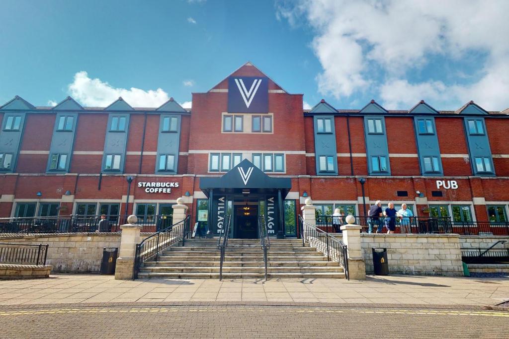 a large red brick building with stairs leading to the front at Village Hotel Cardiff in Cardiff