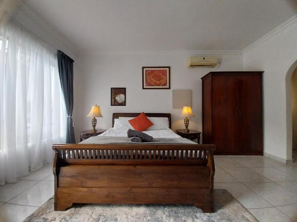- une chambre avec un grand lit en bois et des oreillers rouges dans l'établissement The Freshwater Pearl, à Pretoria