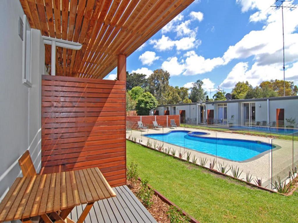 a backyard with a wooden pergola and a swimming pool at Riverside Ocean Grove in Ocean Grove
