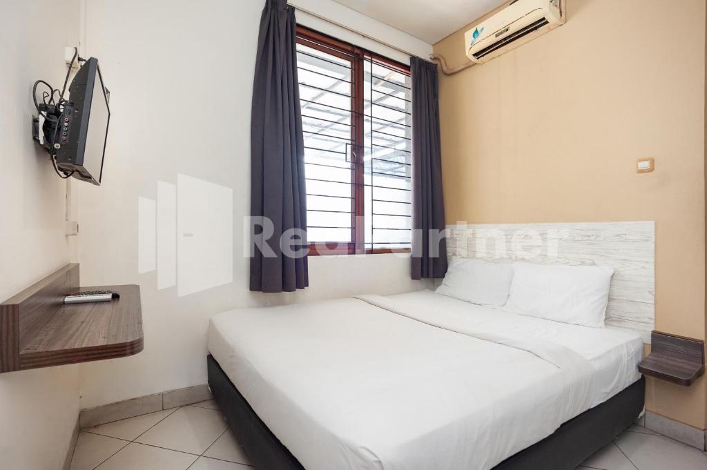 una camera con un letto bianco e una finestra di One 2 Residence near Slipi Jaya Mall Mitra RedDoorz a Giacarta