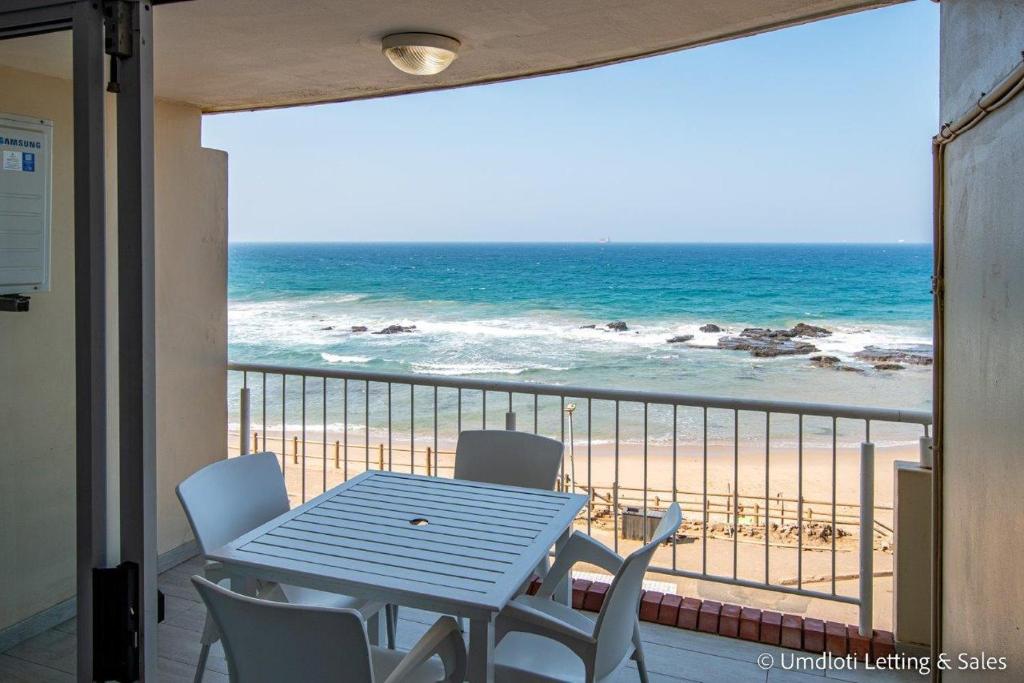 a table and chairs on a balcony with a view of the beach at Cozumel 218 in Umdloti