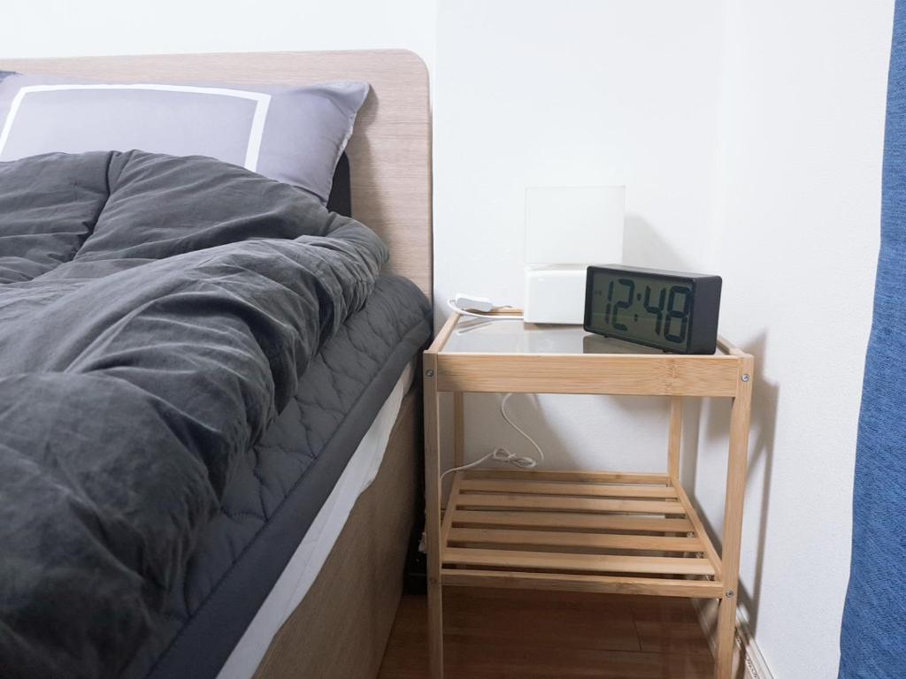 a bed with a night stand next to a clock at Changdong Property in Seoul