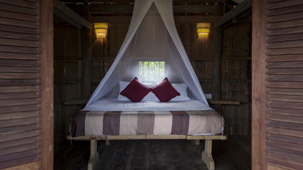 1 cama con 2 almohadas rojas en una habitación en Champa Lodge, en Kampot