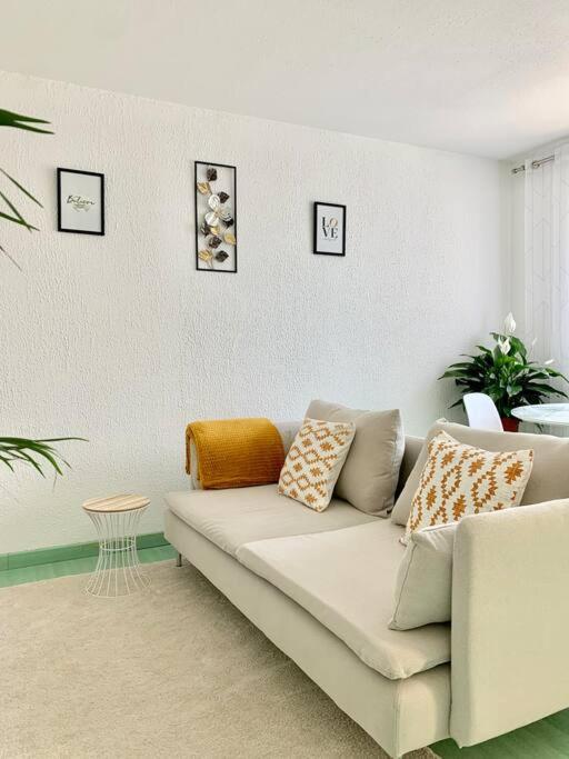 un salon avec un canapé blanc avec des oreillers dans l'établissement Springfields - Appart en résidence proche du parlement européen, à Schiltigheim