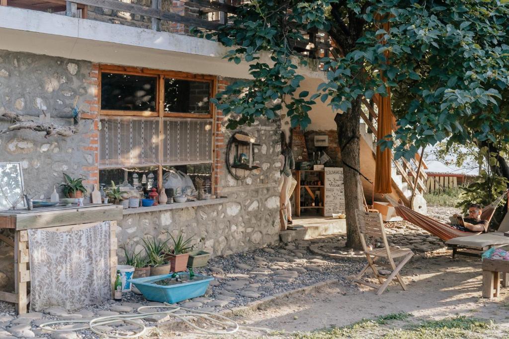 un edificio de piedra con un banco y un árbol en The house in the village en Tirana