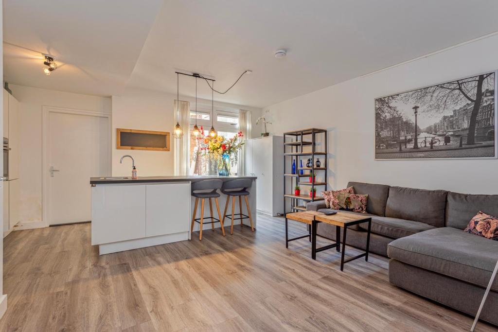 een woonkamer met een bank en een keuken bij Kerkakker0 Luxery apartment with garden in the city center in Eindhoven
