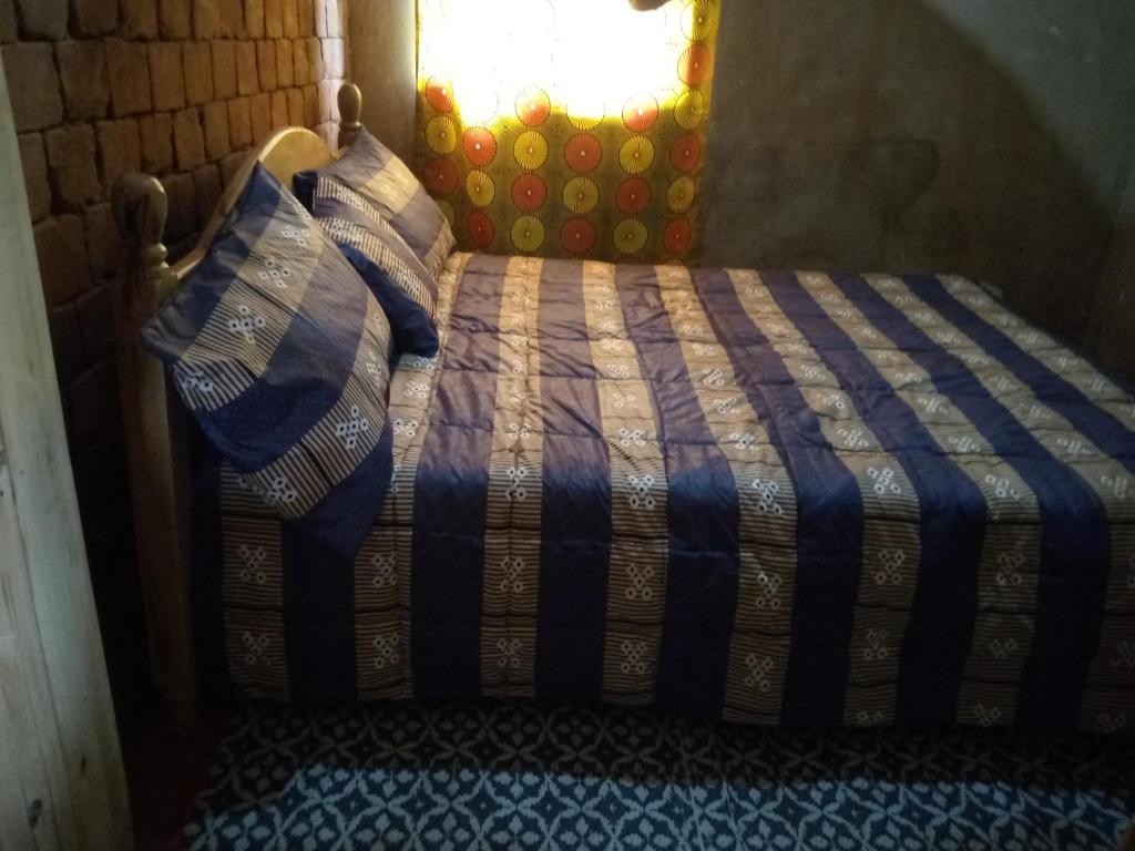 1 cama con edredón azul y blanco y ventana en Munyana homestay, en Akagera