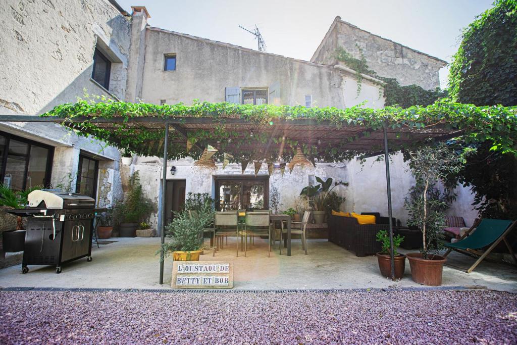 a patio with a table and chairs under a pergola at Oustaou de Betty et Bob in Le Cailar