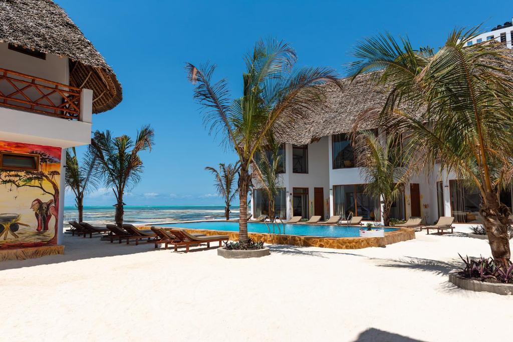 een resort op het strand met palmbomen en een zwembad bij S&S HOTEL in Jambiani