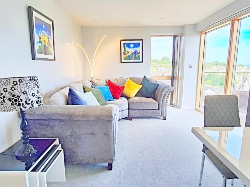 a living room with a couch with colorful pillows at Number 10, Montpellier Apartments, Teignmouth in Teignmouth