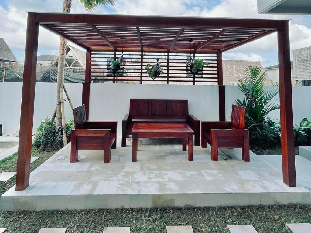 a wooden bench and two chairs on a patio at Mega Canggu Guest House in Canggu