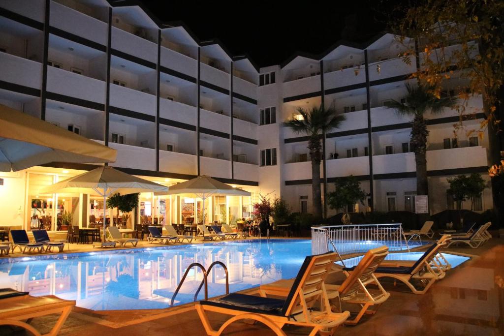 a hotel swimming pool with chairs and umbrellas at night at SİDE SPRİNG HOTEL in Side