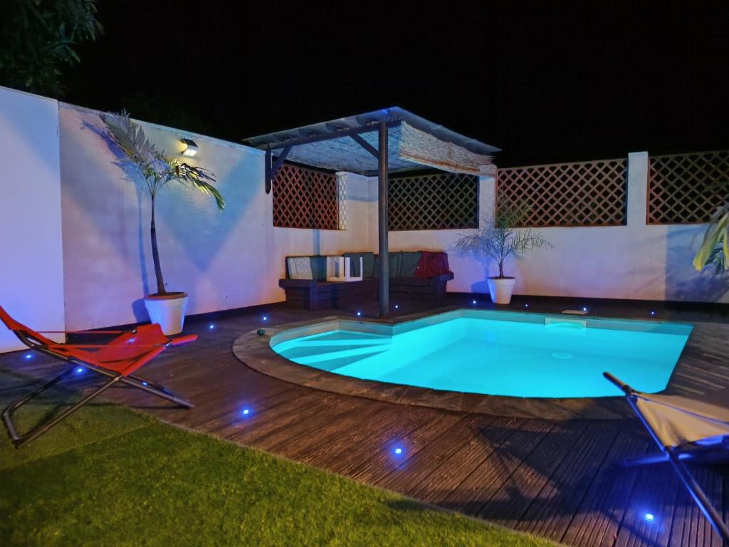a swimming pool in a backyard at night at la casa mangue in Le Diamant