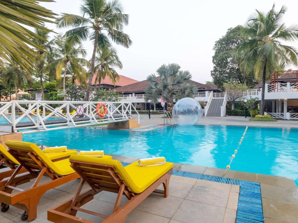 einen Pool mit Stühlen und einem Ball in der Mitte in der Unterkunft Novotel Goa Dona Sylvia Resort in Cavelossim