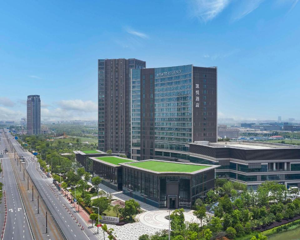 a large building with a green roof next to a highway at Hyatt Regency Shanghai Songjiang in Songjiang