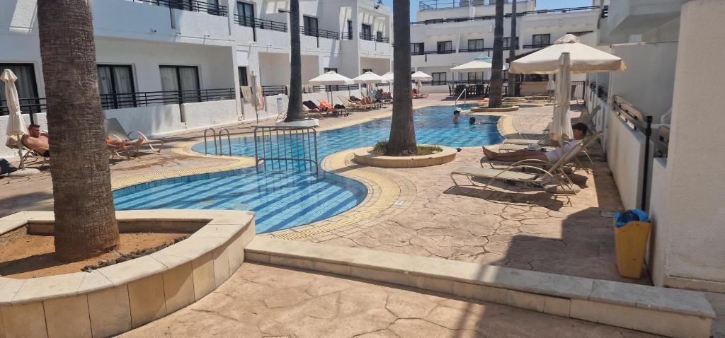 a swimming pool with chairs and umbrellas in a resort at Summer's Hotel Apartments in Ayia Napa