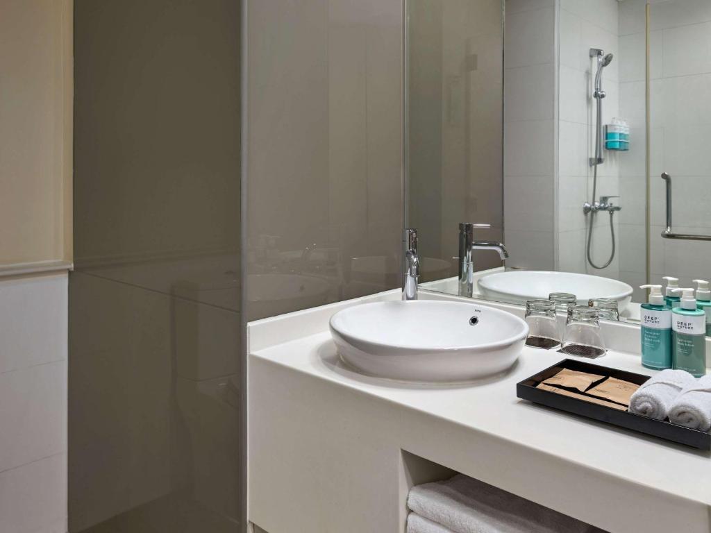 a white bathroom with a sink and a mirror at Novotel Living Saigon South in Ho Chi Minh City
