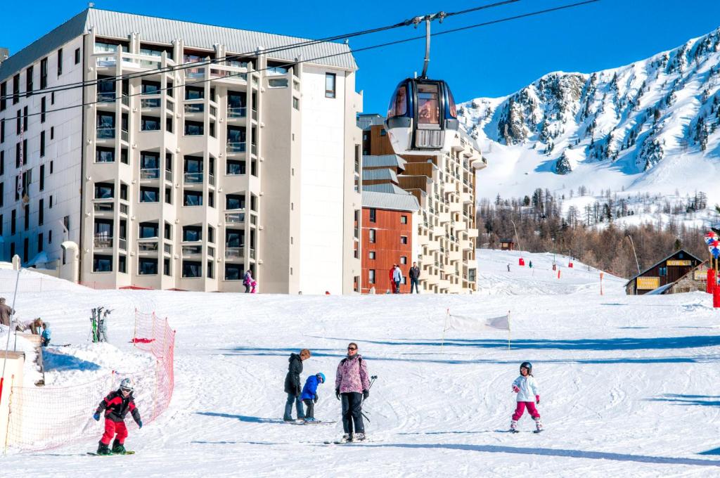 a group of people on a ski slope with a ski lift at SOWELL HOTELS Le Pas du Loup in Isola 2000