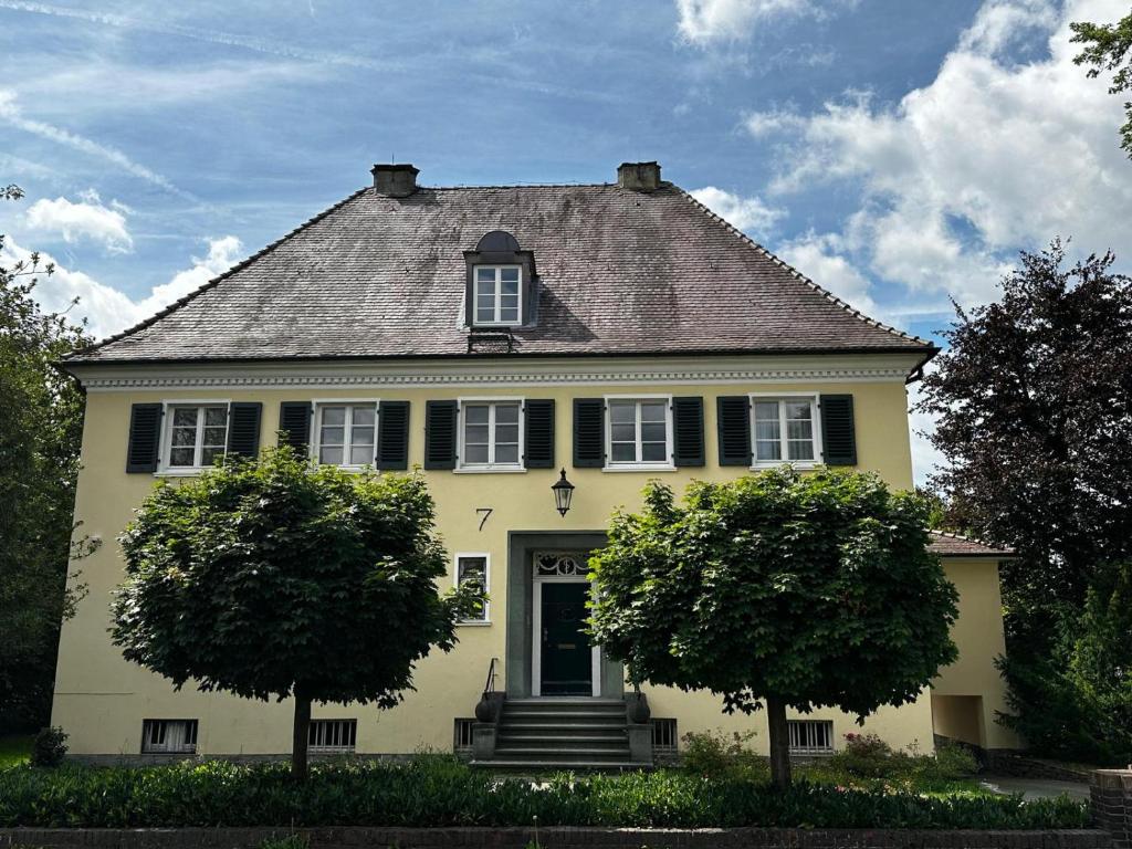 uma casa amarela com duas árvores em frente em VillaWie em Rheda-Wiedenbrück