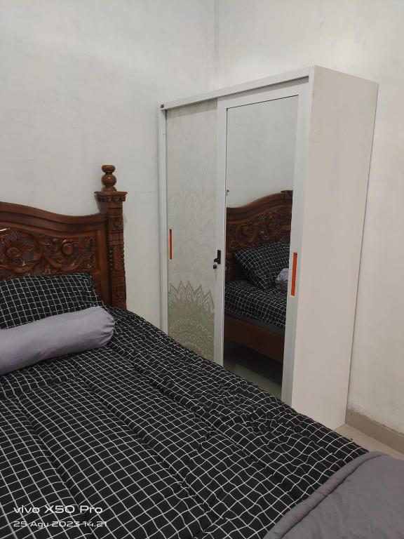 Schlafzimmer mit einem Bett mit einem Spiegel und einer Tür in der Unterkunft Sukayadnya house 3 in Sukasada