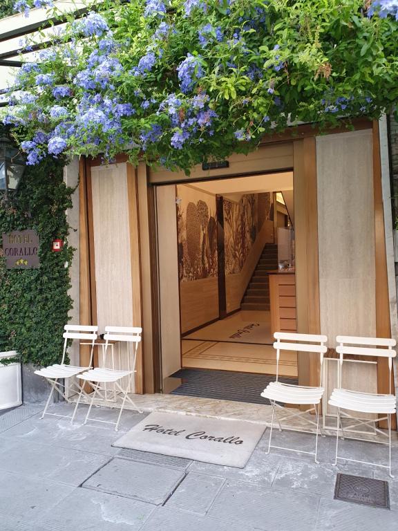 een groep witte stoelen en blauwe bloemen voor een gebouw bij Hotel Corallo in La Spezia