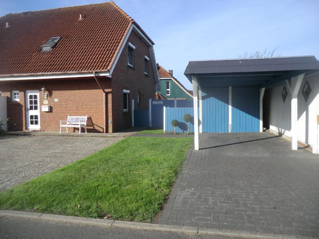 a house with a garage and a bench in a yard at Ferienwohnung im Ferienhaus Kästner in Friedrichskoog