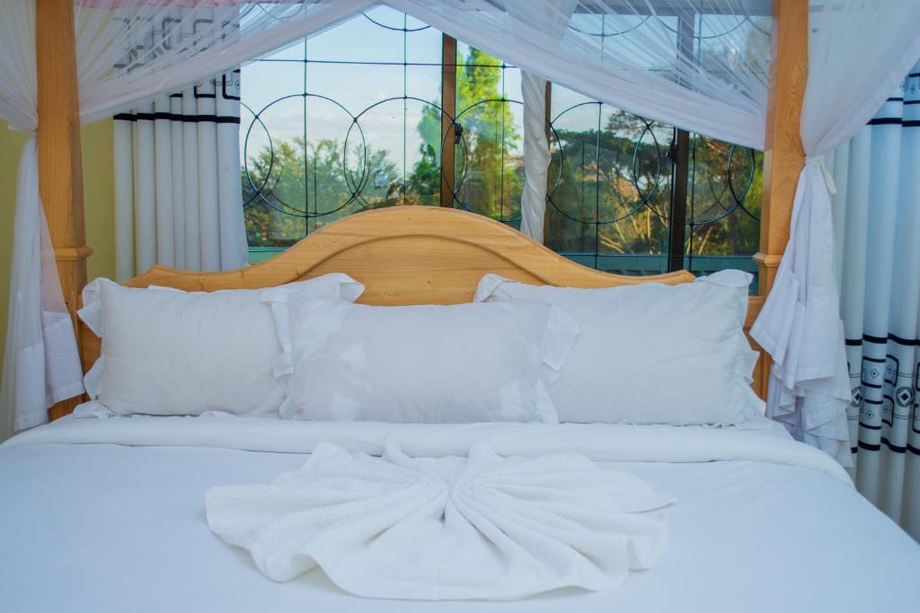 a bed with white sheets and pillows in front of a window at Mzunguu Safari Lodge in Usa River