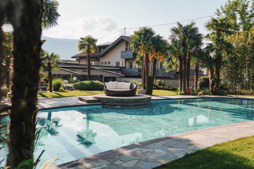 a swimming pool in front of a house with palm trees at Hotel Dorner B&B in Lagundo