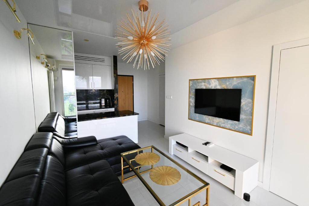 ein Wohnzimmer mit einem schwarzen Ledersofa und einem TV in der Unterkunft Apartament Onyx Modern Tower in Gdynia
