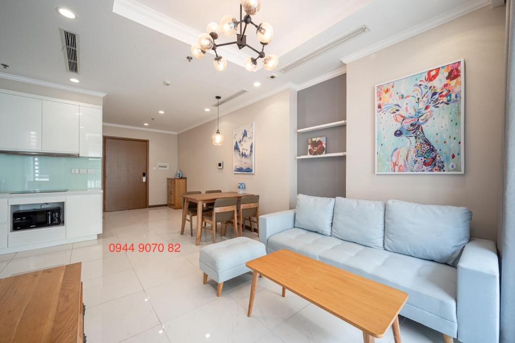 Landmark Vinhomes Christine Apartment في مدينة هوشي منه: غرفة معيشة مع أريكة زرقاء وطاولة
